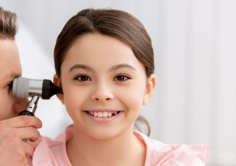 ent physician examining ear of cheerful kid with otoscope