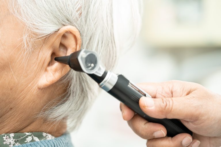 Audiologist or ENT doctor use otoscope checking ear of asian sen